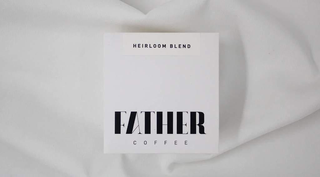 Card with 'Heirloom Blend' and 'Father Coffee' text on a white fabric background